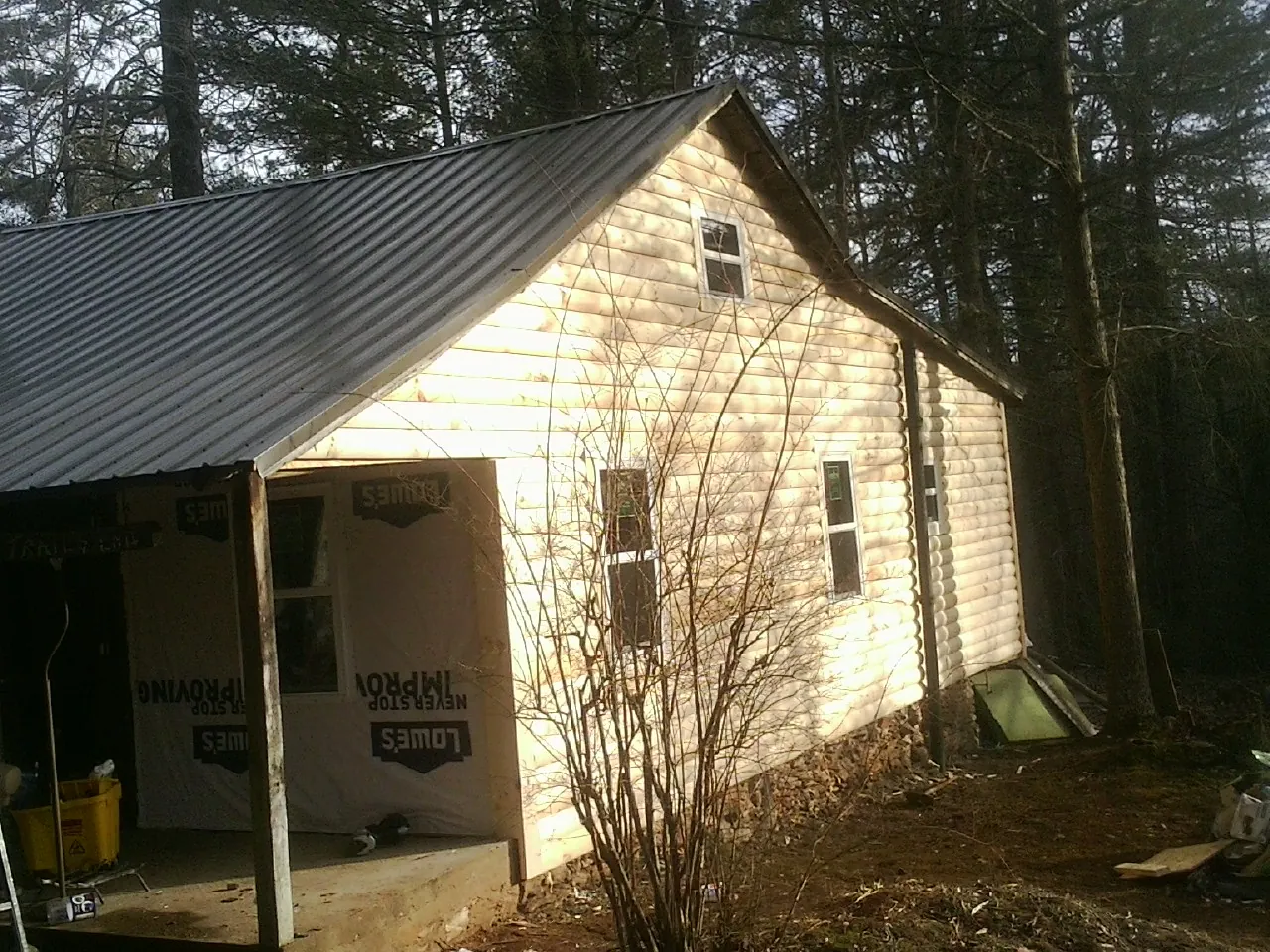 Log siding gable end under a dark metal roof edge in Dodge