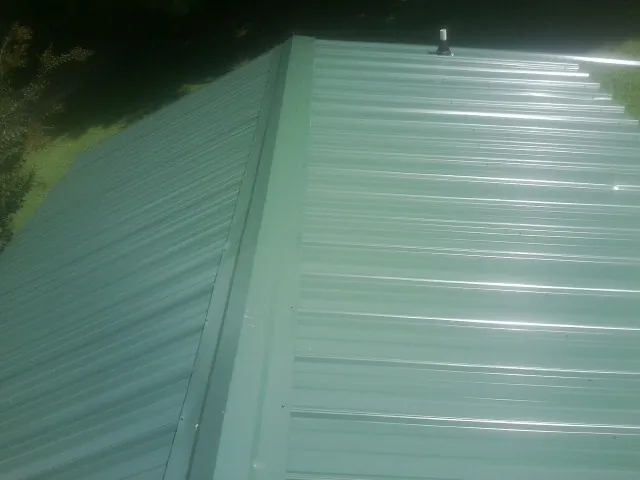 New green metal panels meeting at the ridge of a roof — Flat Roof Repair work by our crew in Dodge